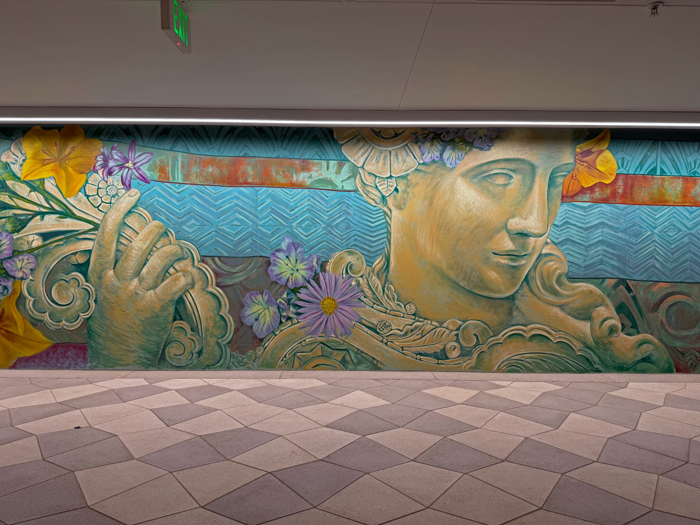 Close view of the classical sculpted face in the "Flourishing Structures" mural at Bloom on Third, framed by gold scrollwork and flowers